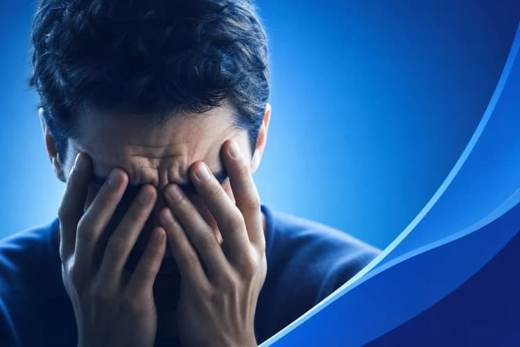 Um close-up de um homem com expressão tensa, com as mãos cobrindo o rosto.