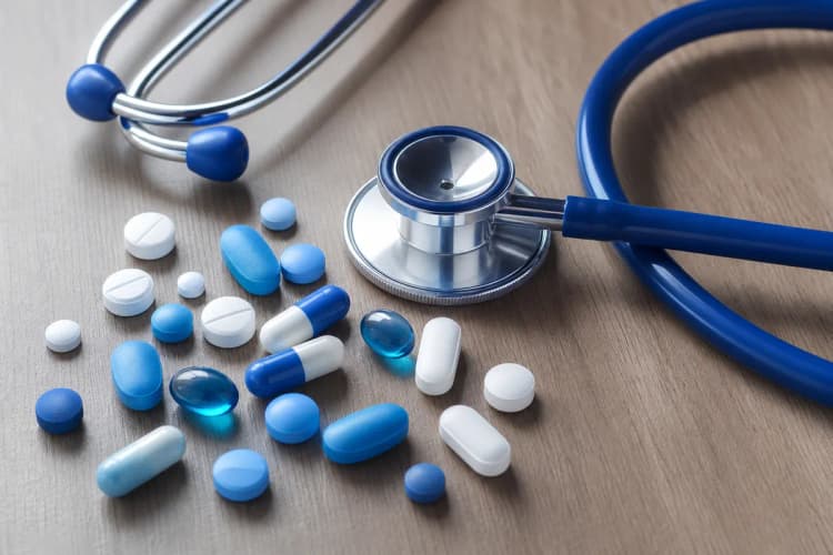 Pílulas e um estetoscópio sobre uma mesa, simbolizando tratamento médico.
